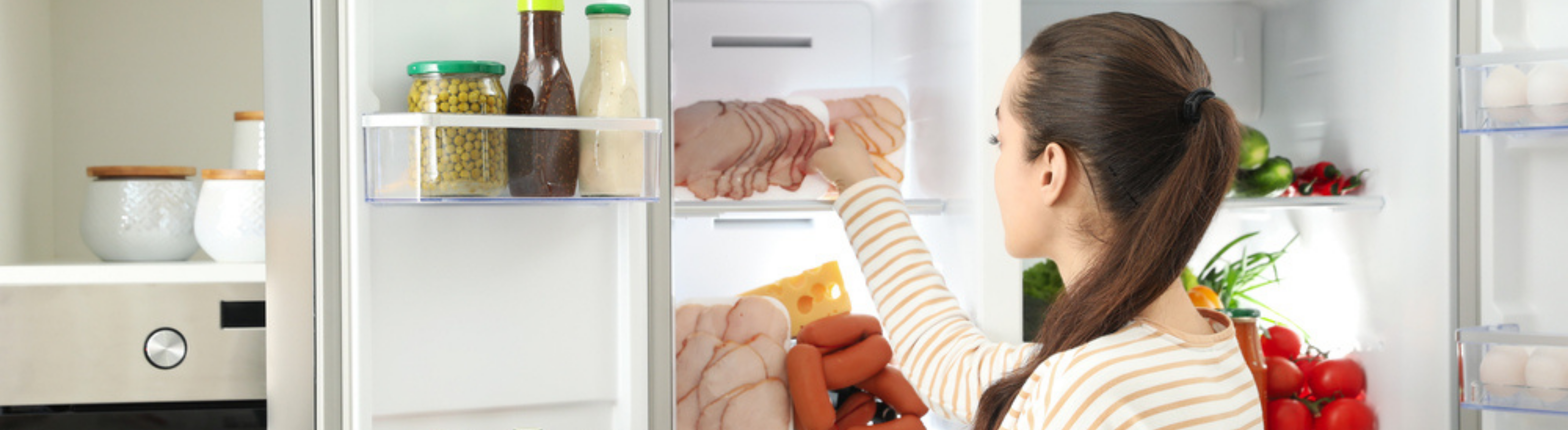 Mulher em frente à geladeira com as portas abertas, pegando alimentos.